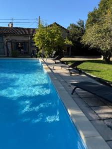 - une piscine avec bancs à côté d'une maison dans l'établissement Gîte avec piscine - La Sacristie, à Graulhet