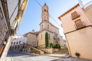 un vieux bâtiment avec une tour d'horloge dans une rue dans l'établissement El Capricho de Alcorisa, à Alcorisa