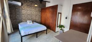 a small bedroom with a bed and a wooden door at Loft Colibrí en Centro Histórico Carmen in Ciudad del Carmen