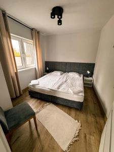 a bedroom with a bed and a chair and a window at Apartamenty Brzozowe in Okoniny Nadjezierne