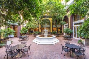 a fountain in the middle of a courtyard with tables and chairs at Hotel Mazarin in New Orleans