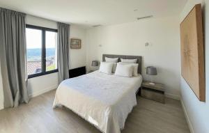 a white bedroom with a bed and a large window at Awesome Home In Fayence in Fayence
