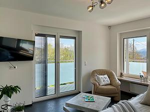 - un salon avec un canapé, une chaise et des fenêtres dans l'établissement Ferienwohnung Margarethe, à Velden am Wörther See