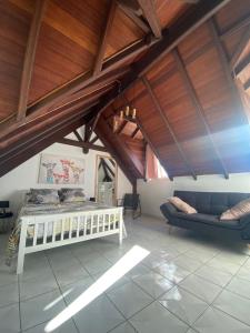 een slaapkamer met een bed, een bank en houten plafonds bij O'Morne in Sainte-Anne