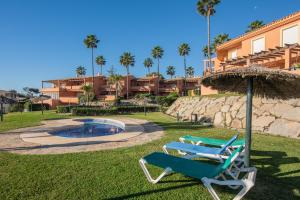 two lounge chairs and an umbrella next to a swimming pool at Fantastic beachfront apartment in Estepona