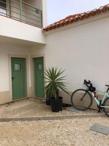 a bike parked next to a building with green doors at Consciência Viva in Encarnação