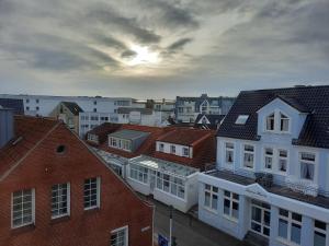 a group of buildings in a city with the sunset at Ferienwohnung Möwennest by Deju in Norderney