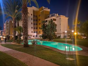 a swimming pool in front of a hotel at night at Spacious ground floor apartment in Punta Prima