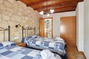 two beds in a room with a stone wall at Casa Calera in Arbuniel +23 photos