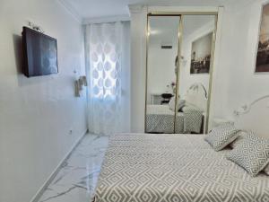 トレモリノスにあるHabitaciones Torremolinosのベッドと鏡のある白い寝室
