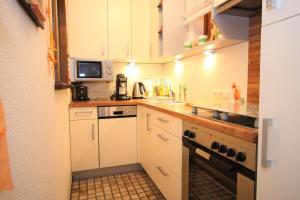 a small kitchen with white cabinets and a stove at Ferienwohnung Hinterthal in Hinterthal +4 photos