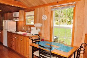 a kitchen with a table with chairs and a window at Plymouth Rock Camping Resort Rustic Cabin in Elkhart Lake