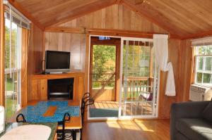 Cette chambre comprend un salon doté d'une télévision et d'un canapé. dans l'établissement Plymouth Rock Camping Resort Deluxe Cabin 16, à Elkhart Lake