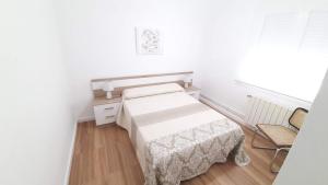 Kleines weißes Zimmer mit einem Bett und einem Stuhl in der Unterkunft Apartamento San Juan in Casas-Ibáñez