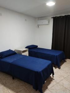 two beds in a room with blue sheets at Departamentos Don Julio in Guaraní +14 photos