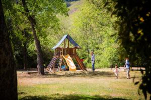 een gezin dat speelt in een park met een speeltuin bij Morgan Hill Camping Resort Cottage 3 in San Martin