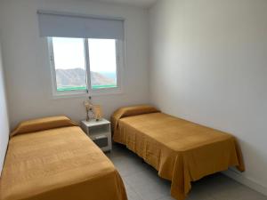 two beds in a room with a window at Monte Paraíso Beach in Puerto Rico de Gran Canaria