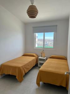 two beds in a white room with a window at Monte Paraíso Beach in Puerto Rico de Gran Canaria
