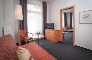 ハレ・ヴェストファーレンにあるHotel Hollmannのベッドとテレビが備わるホテルルームです。