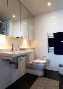 a white bathroom with a sink and a toilet at Stadium Retreat in Sydney +7 photos