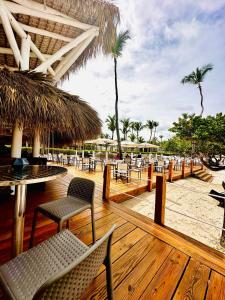 um deque com cadeiras e mesas numa praia em Beach Front Luxury apartment Punta Cana L-101 em Punta Cana