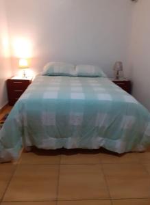 ein Bett mit einer blauen und weißen Bettdecke in einem Schlafzimmer in der Unterkunft Pernoctancia in La Pampilla