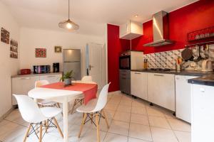 a kitchen with a white table and red walls at Au fil de l'o - Gîte 6 personnes in Locminé +17 photos