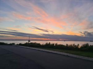 un coucher de soleil sur l'eau avec une route et un bateau dans l'établissement Luxury Panoramic View - By Traum Ferienwohnungen, à Stege