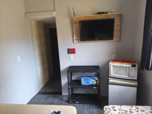 a small room with a microwave and a tv at Cantinho Tá Maneiro in Mongaguá