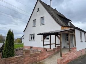 a white house with a black roof and a brick wall at Ferienwohnung Nickel in Hofstetten