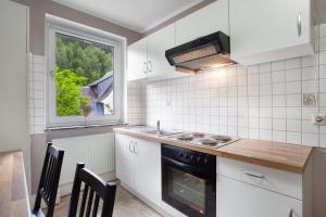 a kitchen with a stove and a sink and a window at Ferienwohnungen Roth in Willingen