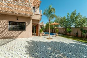 a courtyard of a house with a palm tree and an umbrella at Villa Mazigh & piscine in Marrakech