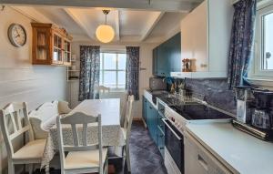 a kitchen with blue cabinets and a table and chairs at Awesome Home In Skiftun With House Sea View in Nesvik