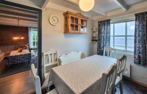 a dining room with a table and chairs and a clock at Awesome Home In Skiftun With House Sea View in Nesvik