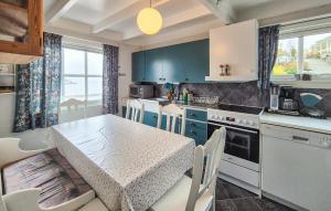 a kitchen with blue cabinets and a table with chairs at Awesome Home In Skiftun With House Sea View in Nesvik