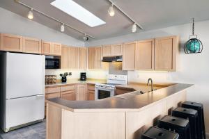 a kitchen with wooden cabinets and a white refrigerator at Oceanfront Views! Hot Tub! Starlit Shores in Yachats +9 photos