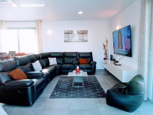 a living room with a black leather couch and a table at Villa Luz 37 - Jacuzzi Terrace & Swimming Pool in Albufeira