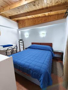 a bedroom with a blue bed and wooden ceilings at Hostal Julia in El Quisco