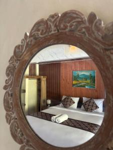 lustro odzwierciedlające sypialnię z łóżkiem w obiekcie Pomelo Guest House w mieście Ubud