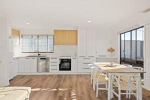 een keuken met witte kasten en een tafel met stoelen bij Seahaven Views in Ventnor +10 foto's
