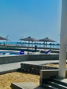 a beach with umbrellas and chairs and the ocean at RIVERA"For Family" in Ras Sedr +2 photos
