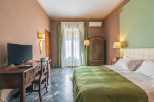 a hotel room with a bed and a desk with a television at Casa Neathon - Whole House 14 guest in Noto
