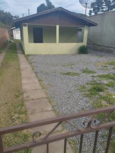 ein gelbes Haus mit einem Zaun davor in der Unterkunft Casa inteira com pátio in Canela + 9 Fotos