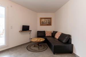 a living room with a black leather couch and a table at La Providence in Annecy