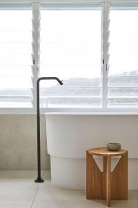 a bath tub sitting next to a window with a table at Calabash Bay Lodge in Berrilee