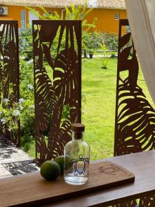 a glass bottle on a table with limes on it at Village Kawann accès plage in Folle Anse