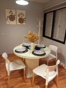 une table de salle à manger blanche avec des chaises blanches et une table avec des assiettes dans l'établissement Cozy apartment, à Mendoza