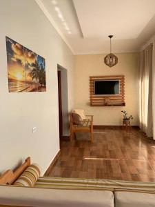 a living room with a couch and a flat screen tv at Casa às margens do Rio Caraíva, área verde in Caraíva