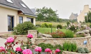 a garden with pink roses in front of a house at Belle maison vue mer 5min de plage in Plouarzel