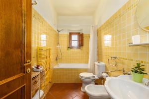 a yellow tiled bathroom with a toilet and a sink at Podere San Bartolo- Fienile in Barberino di Val dʼElsa +31 photos